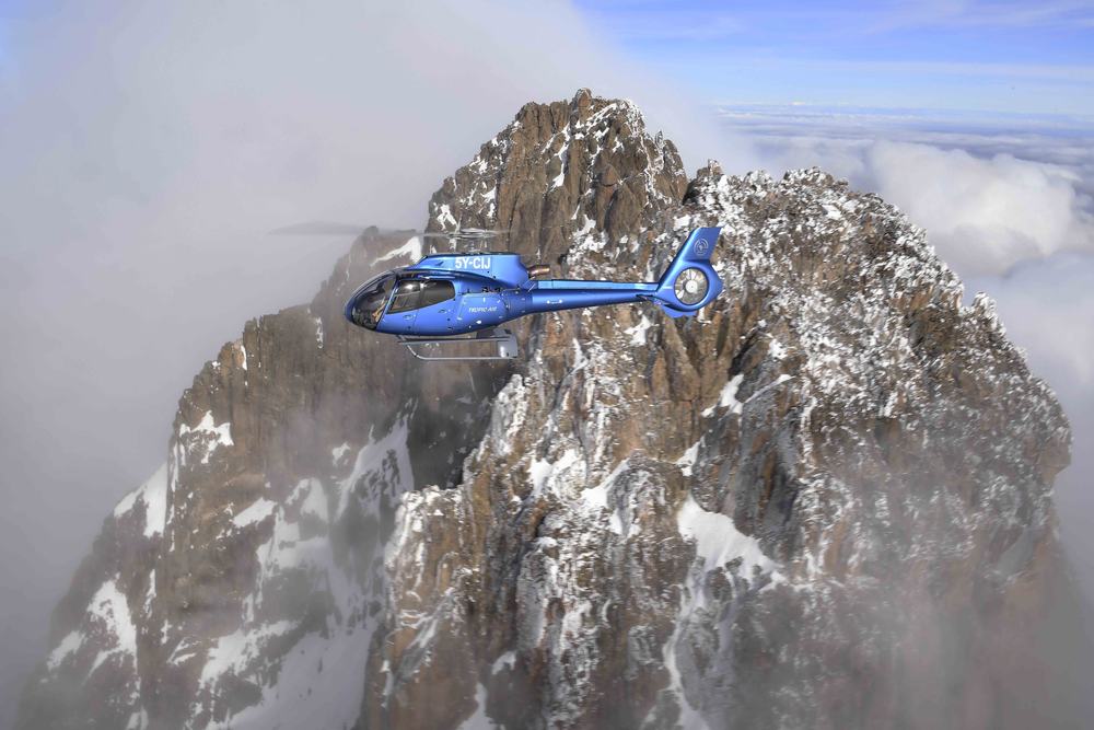 Wide aerial view of a Tropic Air helicopter over Kenya's highlands