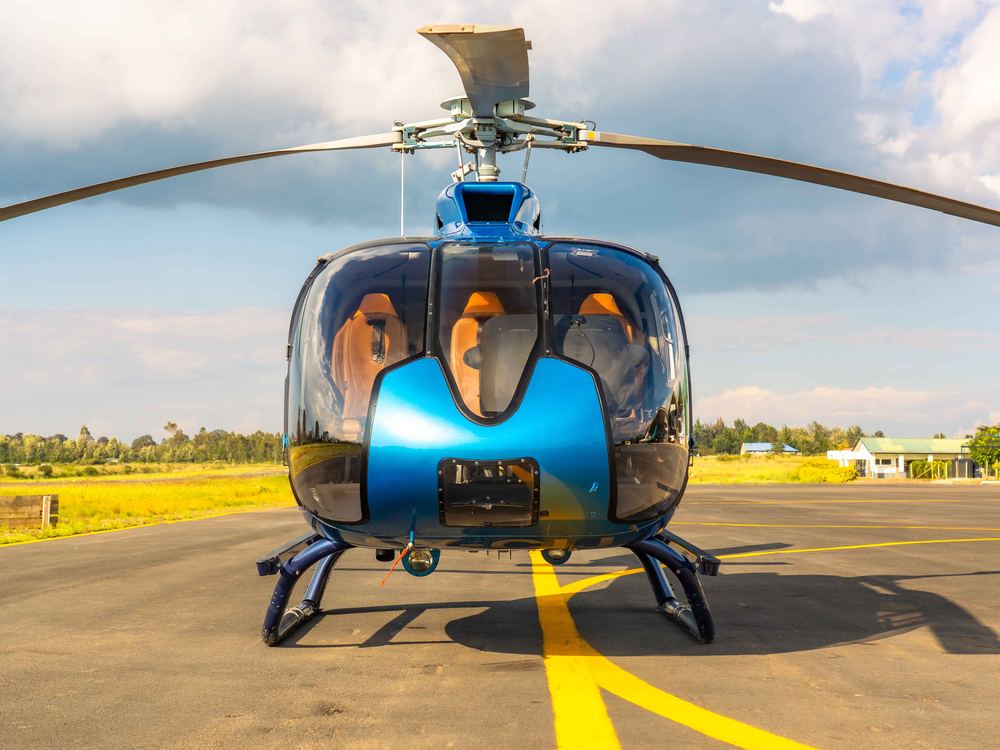 Tropic Air helicopter parked on the grass at golden hour, rotor blades spread